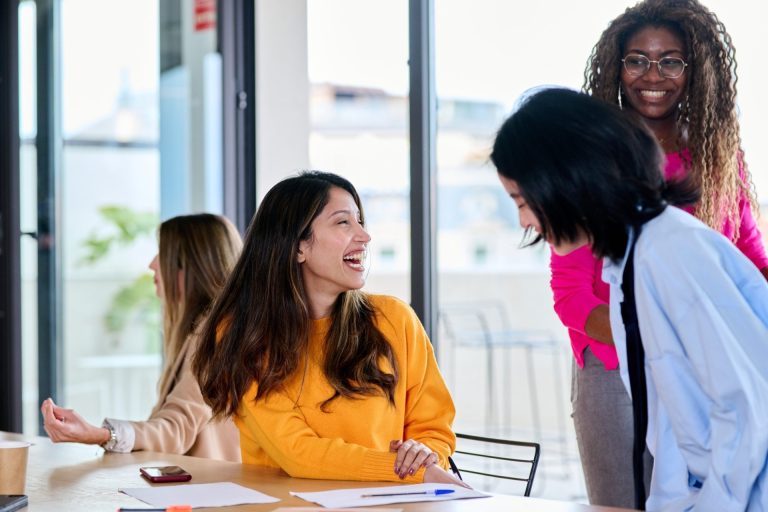 Businesswomen laughing together in the office.