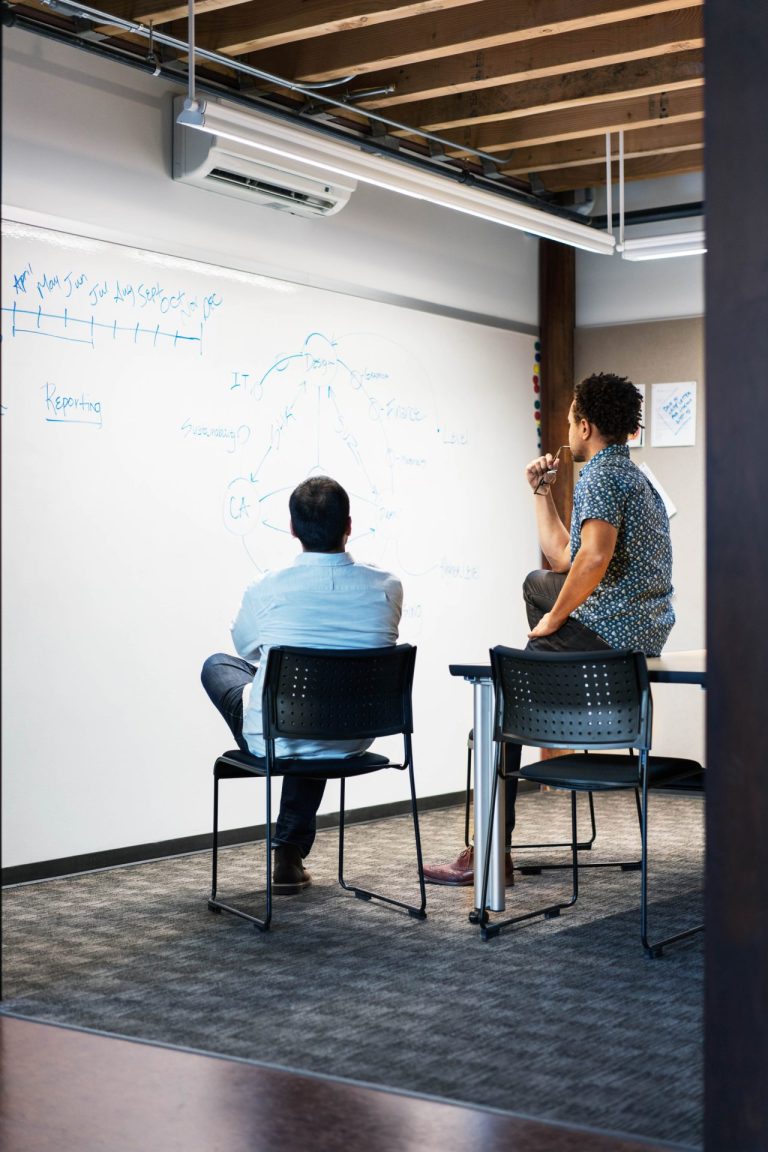 Two men staring at the whiteboard.